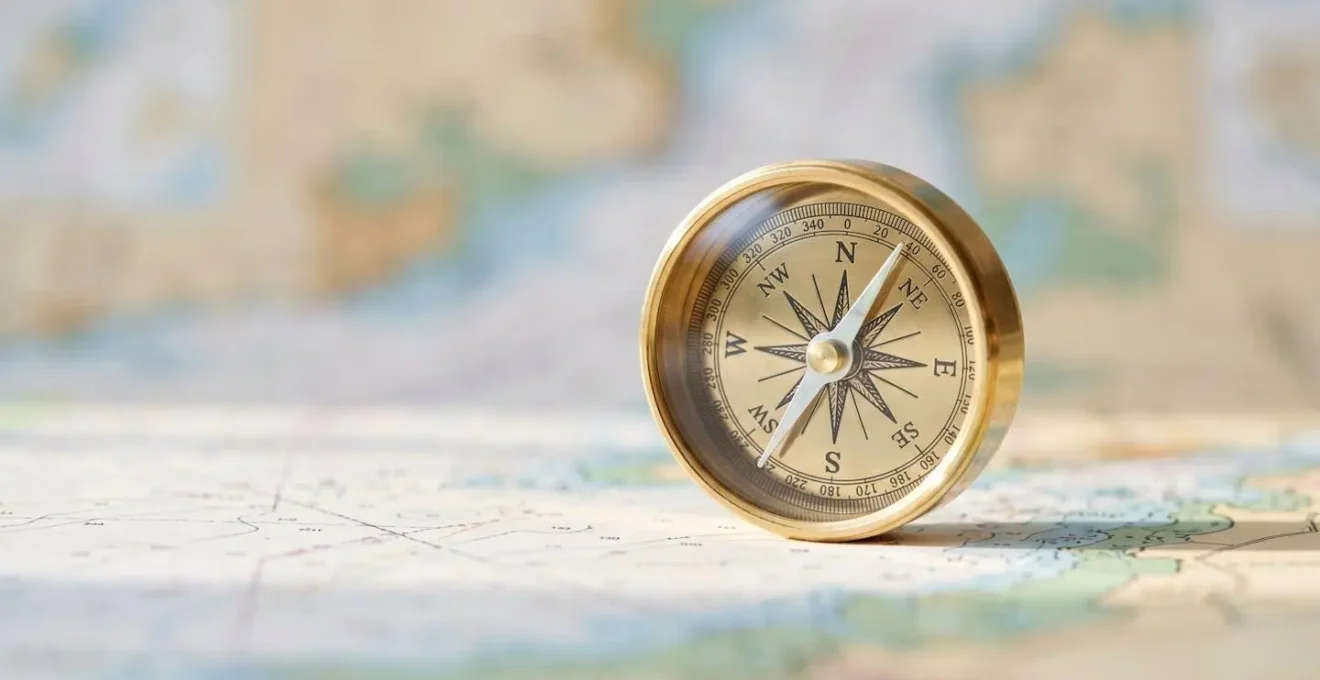 Gros plan artistique sur une boussole posée sur une carte de navigation méditerranéenne floue avec effet bokeh