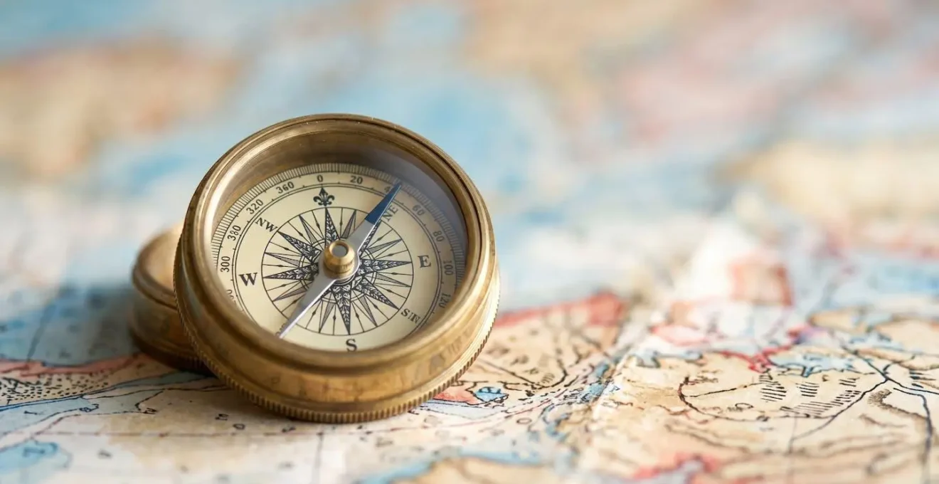 Gros plan artistique sur une boussole posée sur une carte de navigation méditerranéenne floue avec effet bokeh